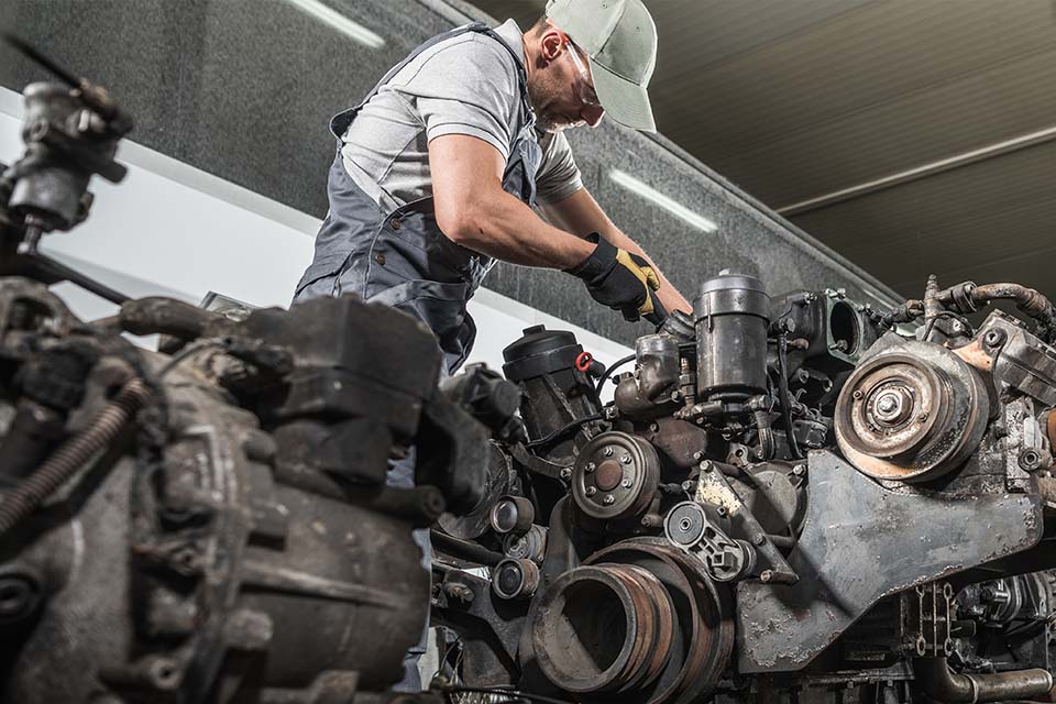 Caucasian Professional Truck Mechanic Rebuilding Heavy Duty Truck Diesel Engine. Automotive Industry Theme.
